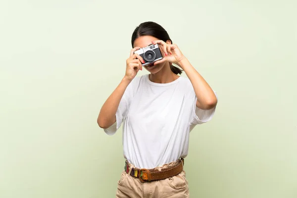 Jovem Mulher Sobre Isolado Fundo Verde Segurando Uma Câmera — Fotografia de Stock