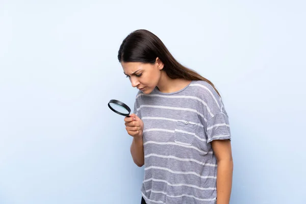 Ung Brunett Kvinna Över Isolerad Blå Bakgrund Håller Ett Förstoringsglas — Stockfoto