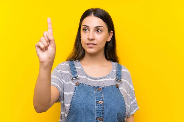 Giovane Donna Salopette Sfondo Giallo Isolato Toccando Sullo Schermo Trasparente — Foto Stock