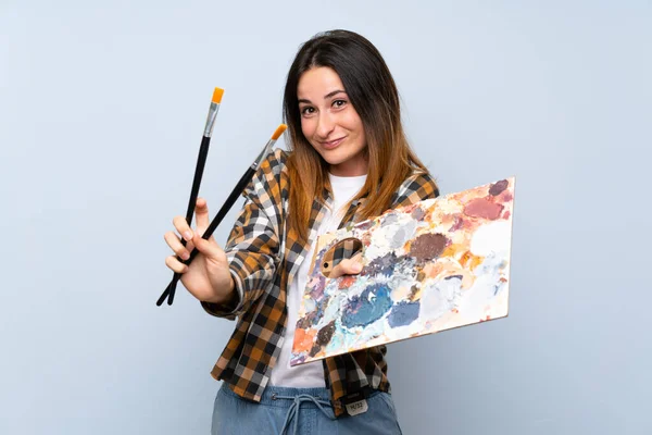 Jovem pintor mulher sobre fundo azul isolado — Fotografia de Stock