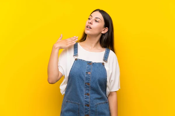 Jovem Mulher Dungarees Sobre Fundo Amarelo Isolado Com Expressão Cansada — Fotografia de Stock