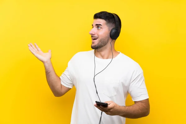 Jovem Homem Bonito Ouvindo Música Com Celular Sobre Parede Amarela — Fotografia de Stock