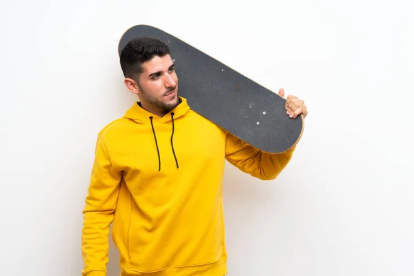 Schöner junger Skater-Mann über isolierte weiße Mauer — Stockfoto