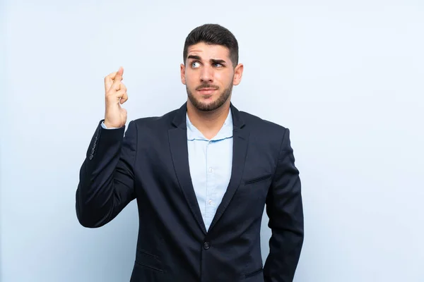 Hombre Guapo Sobre Fondo Azul Aislado Con Los Dedos Cruzando — Foto de Stock