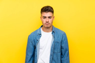 Izole sarı arka plan üzgün üzerinde Genç yakışıklı adam