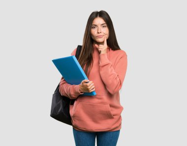 Elinde not defterleri olan genç bir bayan izole edilmiş gri arkaplana bakıyor.