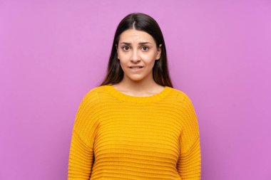 Soyutlanmış mor arka planı olan genç bir kadın şüpheleri var ve kafası karışmış bir yüz ifadesi var.
