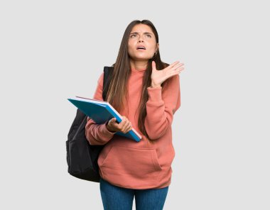 Genç öğrenci kadın tecrit gri arka plan üzerinde kötü bir durum tarafından sinirli defterleri tutan