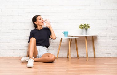 Genç bir kadın yerde oturuyor ve ağzı açık bağırıyor.