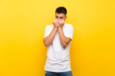 Genç yakışıklı, izole edilmiş sarı arka planda gergin ve korkmuş bir adam elleriyle suni teneffüs yapıyor.