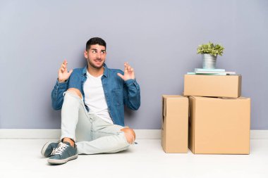 Yakışıklı genç adam parmakları geçiş ile kutular arasında yeni bir evde hareket