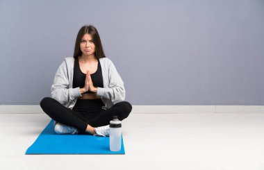 Genç sporcu kadın yerde oturmuş yalvarıyor.