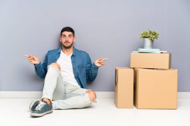 Yakışıklı genç adam kutuları arasında yeni bir evde hareket laterals şüpheleri olan işaret