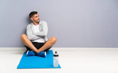 Spor adamı yerde oturuyor, yana bakıyor.