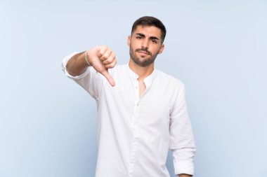 Mavi arka planda sakallı yakışıklı bir adam olumsuz bir ifadeyle baş parmağını aşağı gösteriyor.