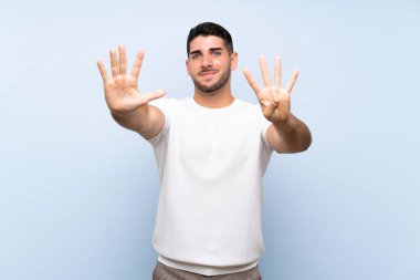 Kafkas yakışıklı adam izole edilmiş mavi arka planda dokuz parmaklı sayıyor.