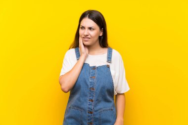 Dişleri ağrıyan, izole edilmiş sarı arka planı olan genç bir kadın.