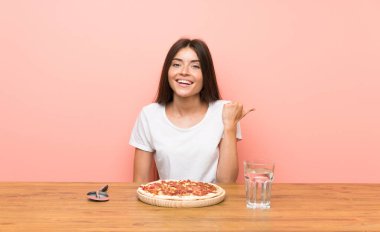 Bir ürün sunmak için yan işaret eden bir pizza ile genç kadın