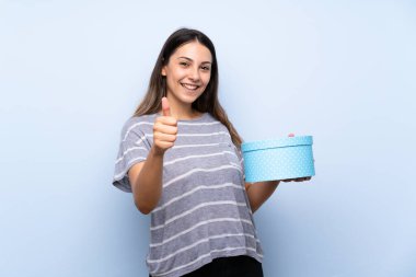 Izole mavi arka plan hediye kutusu tutan üzerinde genç esmer kadın