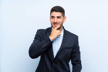 Yakışıklı bir adam mavi arka planda, yana bakıyor.