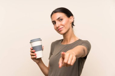 Elinde kahve lekesi tutan genç bir kadın kendinden emin bir ifadeyle seni işaret ediyor.