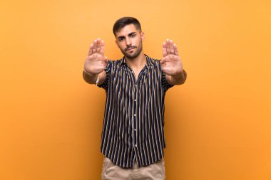 Arkaplanda sakallı yakışıklı bir adam dur hareketi yapıyor ve hayal kırıklığına uğruyor.