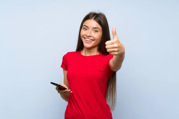 Brunette Jonge Vrouw Met Een Mobiele Telefoon Geïsoleerde Blauwe Muur — Stockfoto