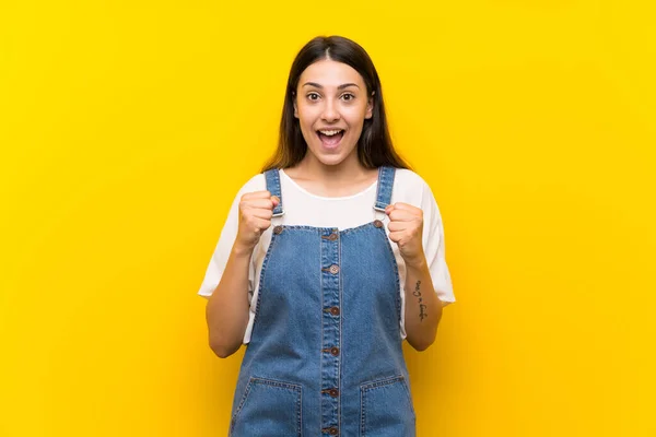 Jovem Mulher Dungarees Sobre Fundo Amarelo Isolado Celebrando Uma Vitória — Fotografia de Stock