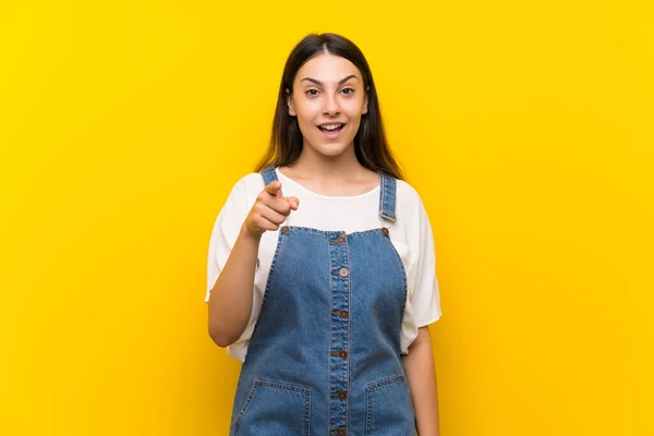 Jonge Vrouw Dungarees Geïsoleerde Gele Achtergrond Verrast Wijzen Naar Voren — Stockfoto