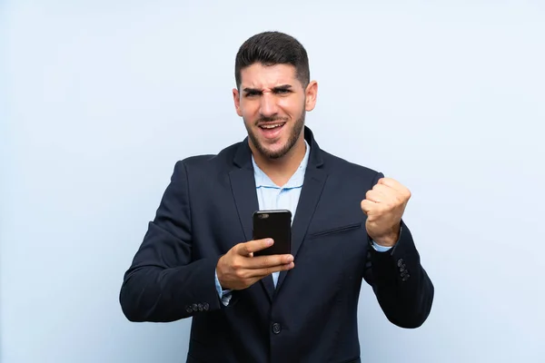 Schöner Mann Über Isoliertem Blauem Hintergrund Mit Telefon Siegesposition — Stockfoto