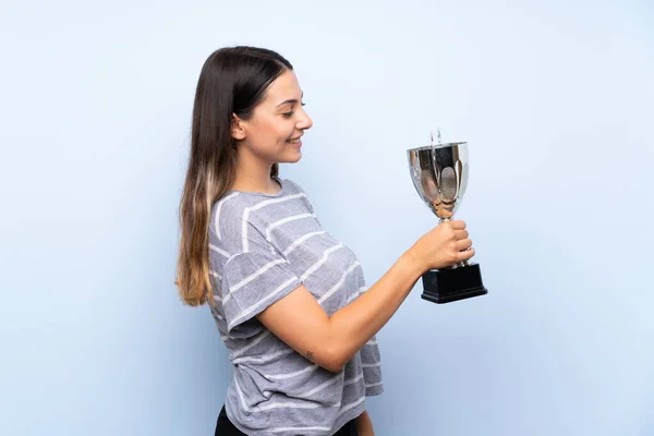 Jovem Morena Sobre Fundo Azul Isolado Segurando Troféu — Fotografia de Stock