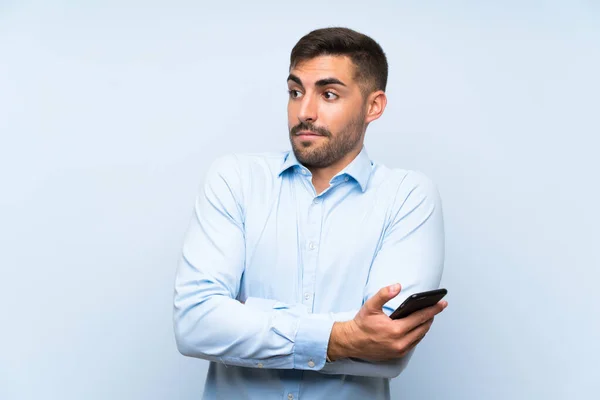 Ung Stilig Man Med Sin Mobil Över Isolerad Blå Vägg — Stockfoto