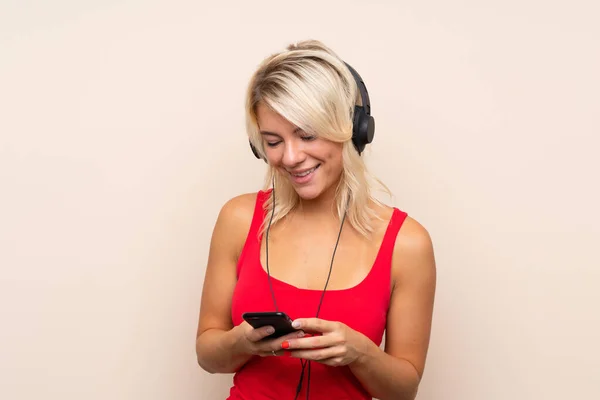 Jeune Femme Blonde Sur Fond Isolé Utilisant Mobile Avec Écouteurs — Photo