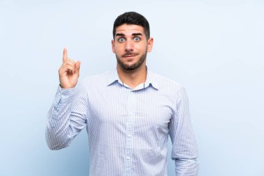 İzole parmak ile işaret izole mavi arka plan üzerinde Kafkas yakışıklı adam harika bir fikir