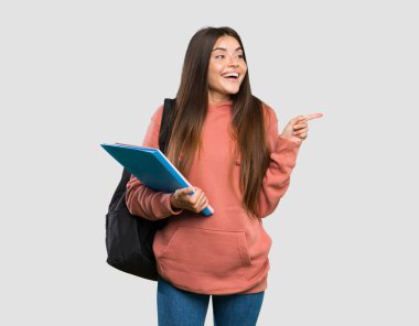 Not defterlerini tutan genç bir bayan, izole edilmiş gri arkaplanı işaret ediyor.