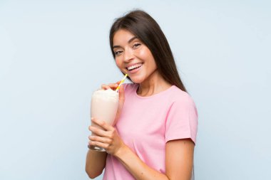 Izole mavi arka plan üzerinde çilek milkshake ile genç kadın