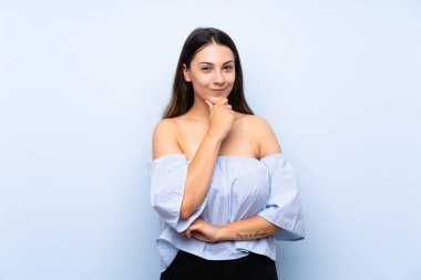 Izole mavi arka plan üzerinde genç esmer kadın gülüyor