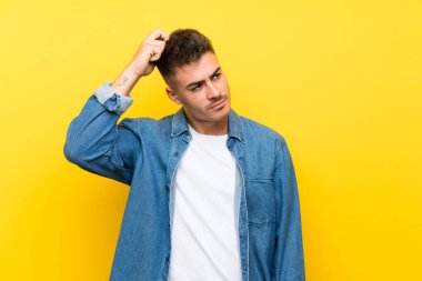 Soyutlanmış sarı arka planda genç yakışıklı bir adam. Şüpheleri var ve kafası karışık.