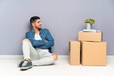 Yakışıklı genç adam yan arayan kutular arasında yeni bir evde hareket