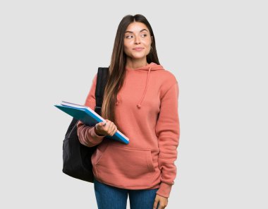 Not defterleri tutan genç bir bayan, izole edilmiş gri arka plana şüpheyle bakıyor.