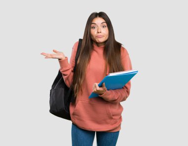 Elinde not defterleri olan genç bir kız öğrencinin, izole edilmiş gri arka plan üzerinde el ele tutuşurken şüpheleri var.