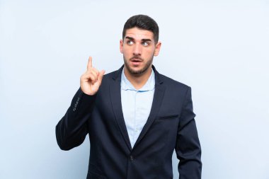 Soyutlanmış mavi arkaplanı olan yakışıklı bir adam bir fikir düşünüyor.