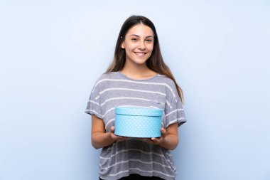 Izole mavi arka plan hediye kutusu tutan üzerinde genç esmer kadın