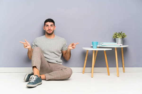 Joven Hombre Guapo Sentado Suelo Señalando Los Laterales Que Tienen — Foto de Stock