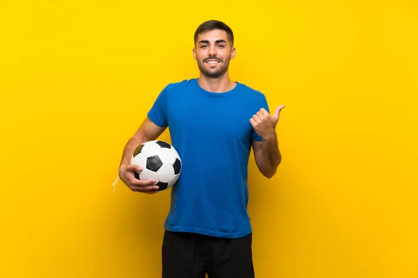 Jovem Jogador Futebol Bonito Homem Sobre Isolado Parede Amarela Apontando — Fotografia de Stock
