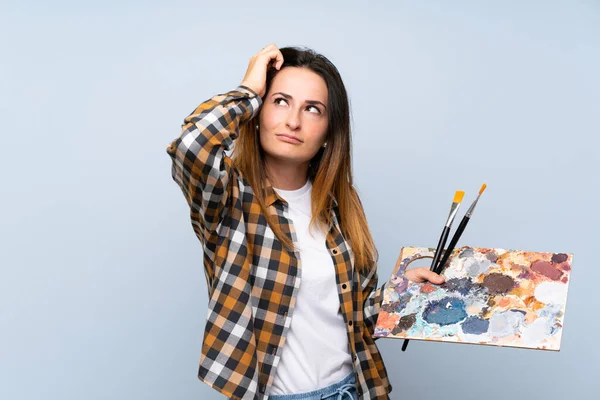 Joven Pintora Mujer Sobre Fondo Azul Aislado Que Tiene Dudas — Foto de Stock