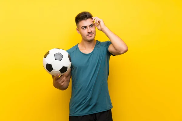 Όμορφος Νεαρός Ποδοσφαιριστής Πάνω Από Απομονωμένο Κίτρινο Φόντο Έχει Αμφιβολίες — Φωτογραφία Αρχείου