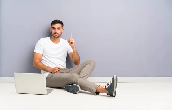 Joven Con Portátil Sentado Suelo Apuntando Con Dedo Índice Una — Foto de Stock