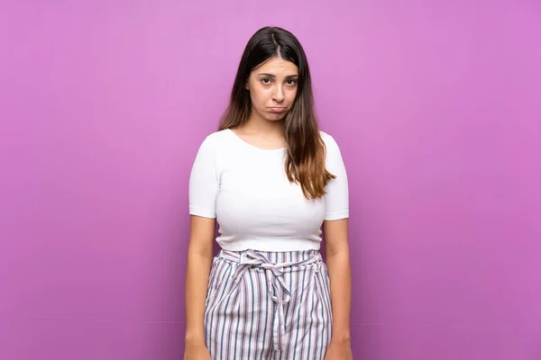 Young woman over isolated purple background with sad and depressed expression