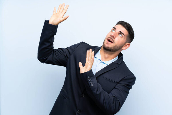 Красивый мужчина на изолированном синем фоне нервничает и боится
